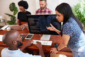 Two developers peer programming together in office, assisting peer review