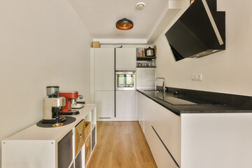 a kitchen area with white cabinets and black counter tops, wood floors and an open door leading to the living room
