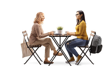 Mature and younger woman sitting at a table and having a cup of coffee