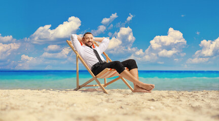 Man in a shirt and pants resting on the beach by the sea