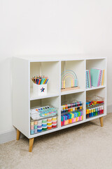 White shelving with various material for creativity and kids art activity. Stationery and supplies for drawing and craft. Organizing and storage in craft room.