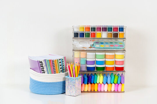 Paints, pencils, plasticine and various material for creativity and kids art activity in containers on shelves. Stationery and supplies for drawing and craft. Organizing and storage craft room.