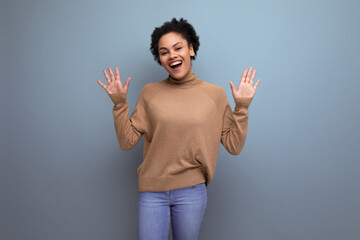 positive young authentic latino woman with afro hair tied up in a ponytail against the background...