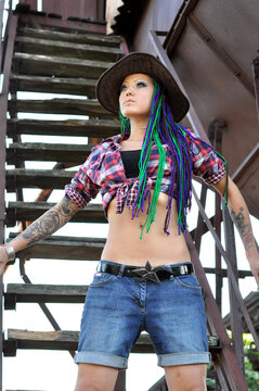 young tattooed  stylish woman with dreadlocks in farmer style