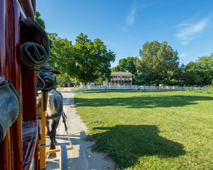 Obraz premium Exterior view of stagecoach traveling along a dirt road towards an 1860's era house