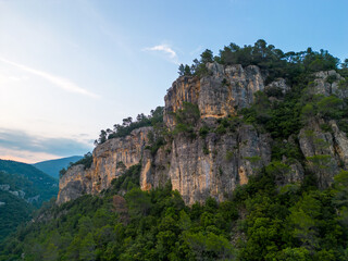 Fototapeta na wymiar Steep rocky cliffs over forested landscape at golden hour