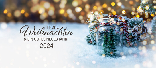 Christmas greeting card with German text Frohe Weihnachten und ein gutes neues Jahr 2024 - Beautiful xmas decoration with Christmas tree in snow - Background banner - 621011659
