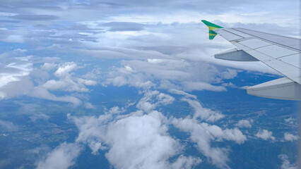 Fototapeta premium Green plane wing view from window with clouds and sea