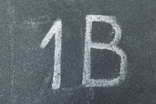 The inscription "1B" on gray rough asphalt