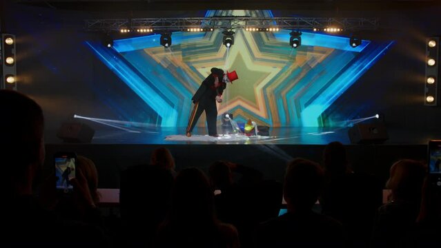 Creepy scary clown mime pretends to cut his hand on stage during TV talent show audition . Broadcast television style TV entertainment program 