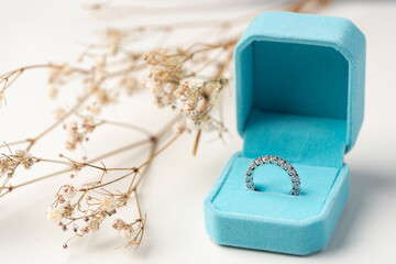 Golden diamond ring in the box with white flower background