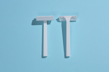 Disposable white plastic razors on blue background. Top view. Creative layout