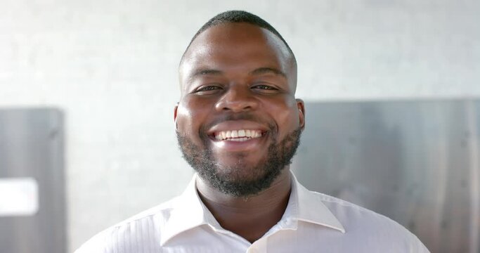 Portrait of happy african american casual businessman with beard smiling in office, slow motion