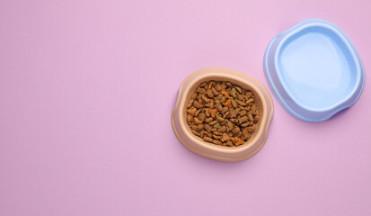 Obraz na płótnie Canvas Pet bowl of dry food and water on a pink background. Top view