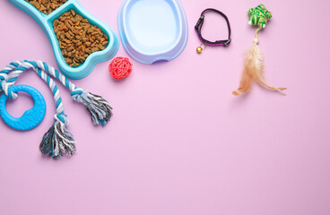 Obraz na płótnie Canvas Many different toys for pets and a bowl of dry food and water on a pink background. Top view. Flat lay. Copy space