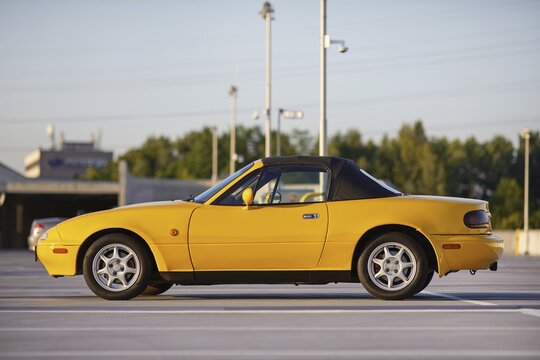 Auto mazda model mx-5   1995 r. w kolorze sun burst yellow gen N po liftingu zaparkowana na parkingu widok z zewnątrz.