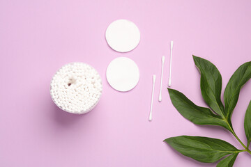 Self hygiene, beauty concept. Cotton ear sticks and pads, green leaves on purple background
