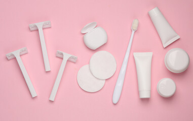 White mockups of beauty products. Just hygiene. Razors, cotton pads, dental floss, toothbrush, tubes and jars of cream on a pink background. Flat lay