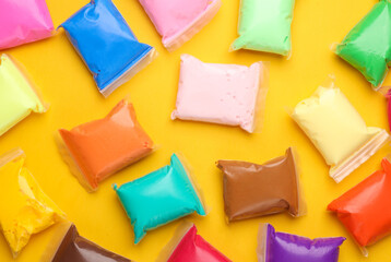 Colored Air plasticine set in packs, yellow background. Children's creativity. Top view.