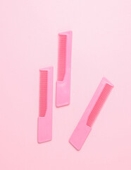 Pink plastic combs on pink background. Beauty and fashion minimalism still life