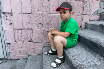 A sad boy is sitting on stone steps