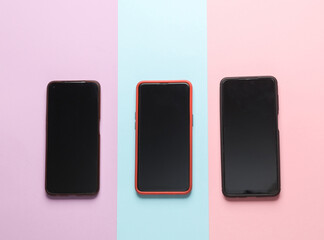 Three smartphones on pastel background. Top view