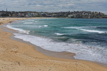 Tourists and beachgoers walk along Bondi Beach while surfers try to ride the waves. Sydney-Australia-722