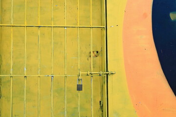 Security grill for chipped yellow wood door on colorist wall along Queen Elizabeth Drive-Bondi Beach. Sydney-Australia-724