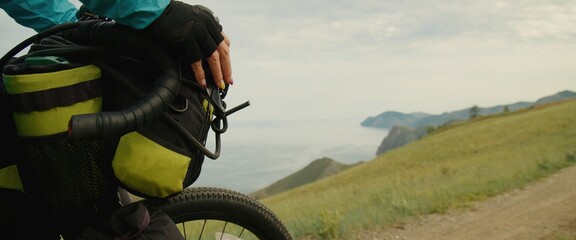 The sporty woman travels on a bicycle with bikepacking bags. The sportswoman traveler journey on bicycle touring in modern style sportswear, helmet and sport glasses in green black colors