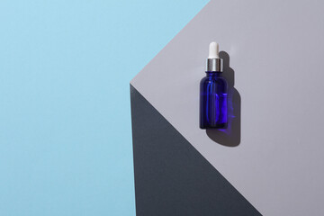 Serum bottle on the corner of gray cube. Optical geometric illusion. Creative layout. Minimalism. Beauty concept