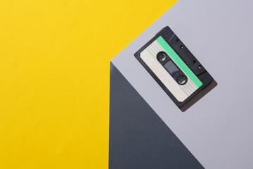 Audio cassette on the corner of gray cube. Optical geometric illusion. Music, retro 80s. Creative layout. Minimalism