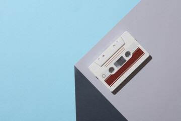 Audio cassette on the corner of gray cube. Optical geometric illusion. Music, retro 80s. Creative...