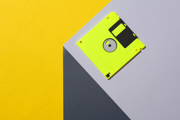 Yellow Floppy disk on the corner of gray cube. Optical geometric illusion. Creative layout. Minimalism. Retro 80s