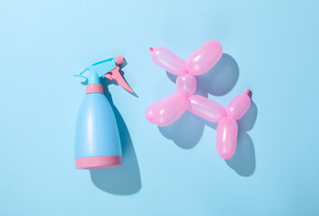 Inflatable balloon in the shape of a dog and a spray bottle on a blue background