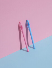Plastic pink and blue pens on a blue-pink background. Business, education concept. Creative layout, minimalism
