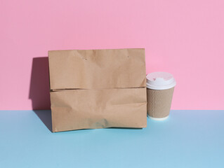 Takeaway food. Zero waste. Craft paper pack and coffee cup on pink blue background. Eco concept.