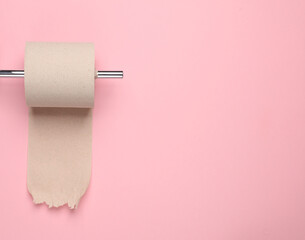Metal Toilet paper holder with a roll of toilet paper on pink background. minimalistic photo