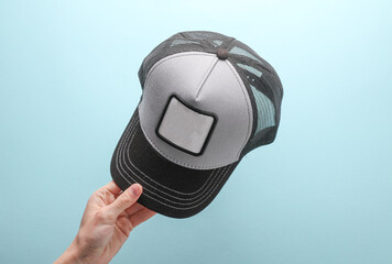 Hand holding Baseball cap mockup with white blank logo on blue background