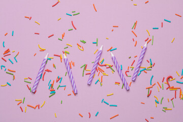 Purple birthday candles with  sprinkles on pastel background. Minimalism party concept