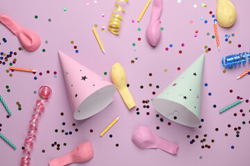Birthday cone caps, confetti, candle and balloons on pastel background. Party concept. Top view