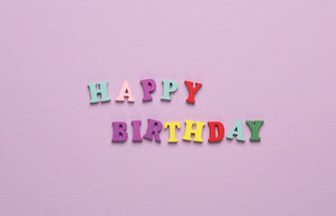 Word happy birthday from colored letters on pink background
