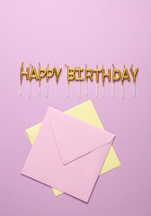 Golden candles in shape of happy birthday letters with envelopes on purple background
