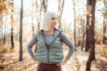 Portrait of blonde fitness woman in sportswear in autumn forest. Outdoor workout
