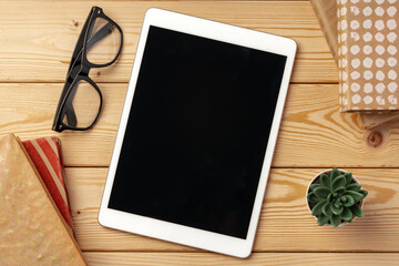 Top view of wooden table with white digital tablet with black screen on it