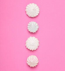 Laid out in row Sweet meringue on pink background. Top view