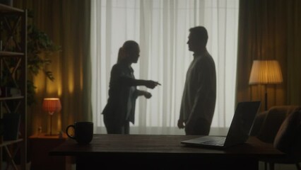 A man and a woman are arguing in the living room near the window. A silhouette of a couple arguing over the fact that the man spends too much time on the laptop. Slow motion. HDR BT2020 HLG Material. - Powered by Adobe