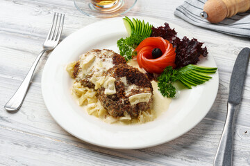 Two beef patties with sauce and fresh vegetables served on plate in cafe
