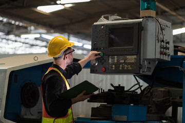 Male engineer worker working and control machine in factory. Male worker working with CNC machine with safety uniform, helmet in industry factory