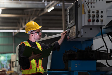 Male engineer worker working and control machine in factory. Male worker working with CNC machine with safety uniform, helmet in industry factory