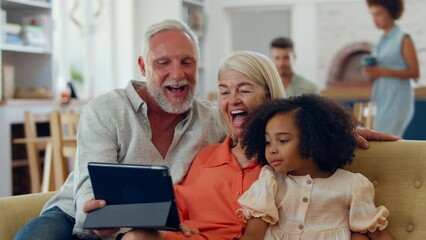 Laughing granddaughter and grandparents on sofa at home streaming show on digital tablet - shot in slow motion - Powered by Adobe
